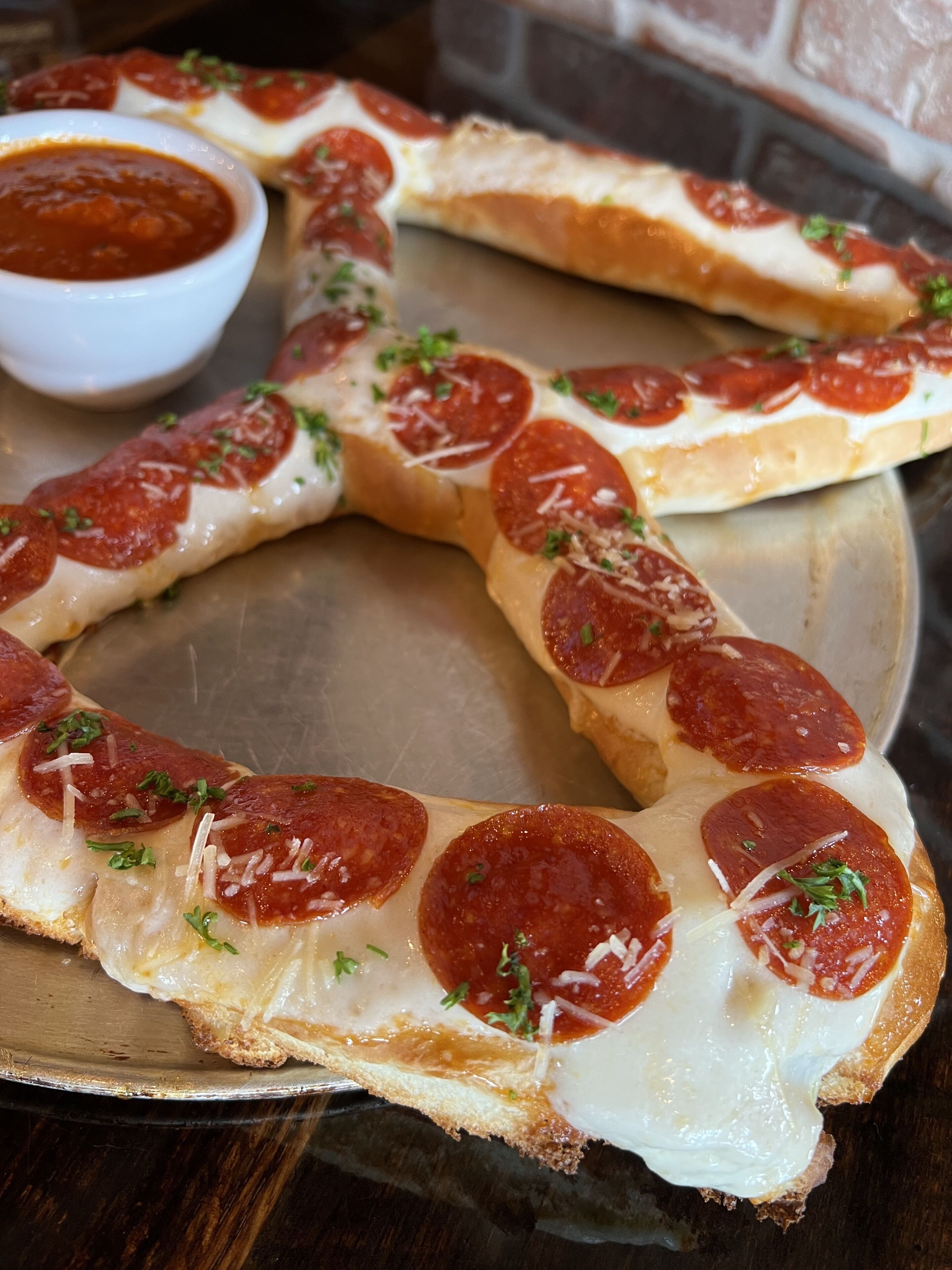 A pizza with pepperoni slices and cheese on a metal tray.