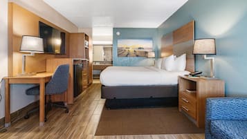 Une chambre d’hôtel avec un lit, un bureau, une chaise et un tableau au mur.