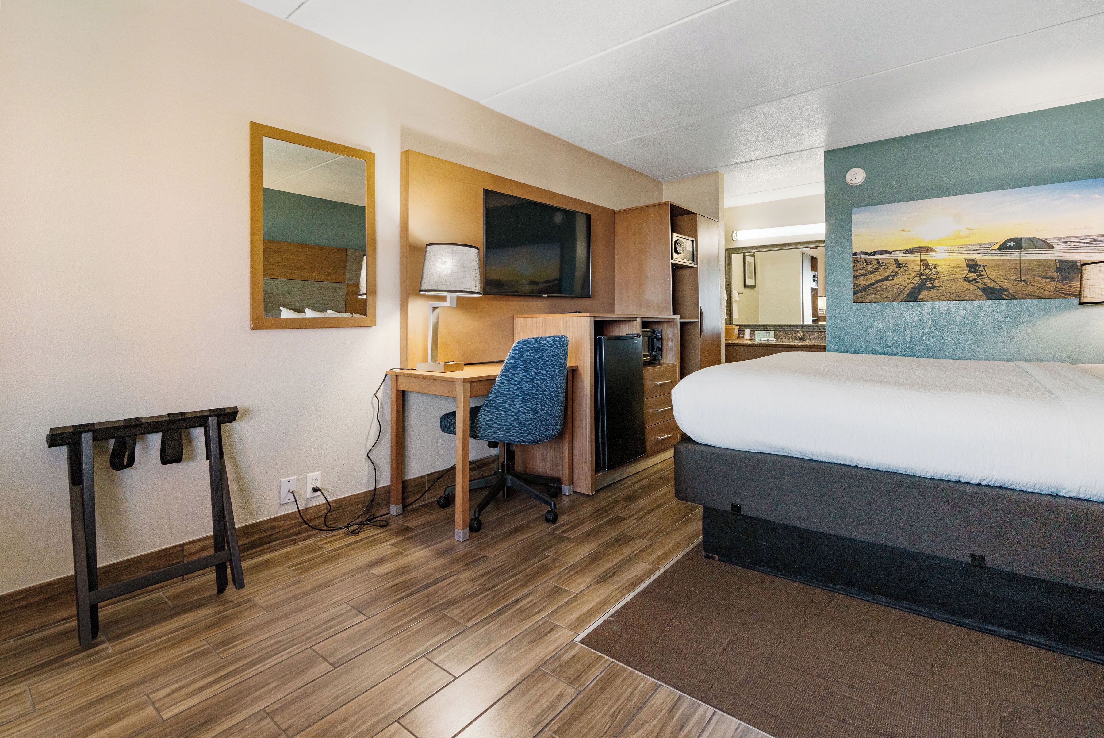 A hotel room with a bed, desk, chair, and a television.