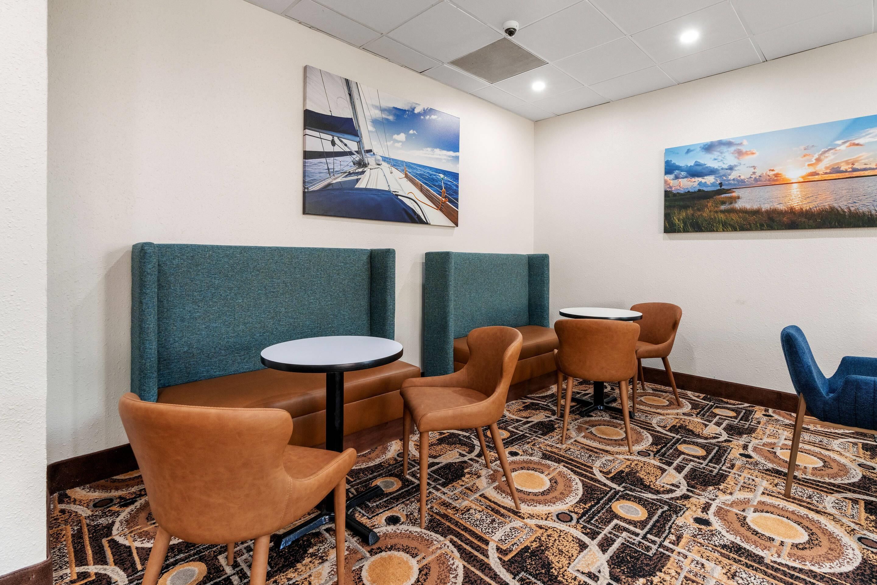 A hotel lobby with seating arrangements, including booths and chairs, and two paintings on the walls.
