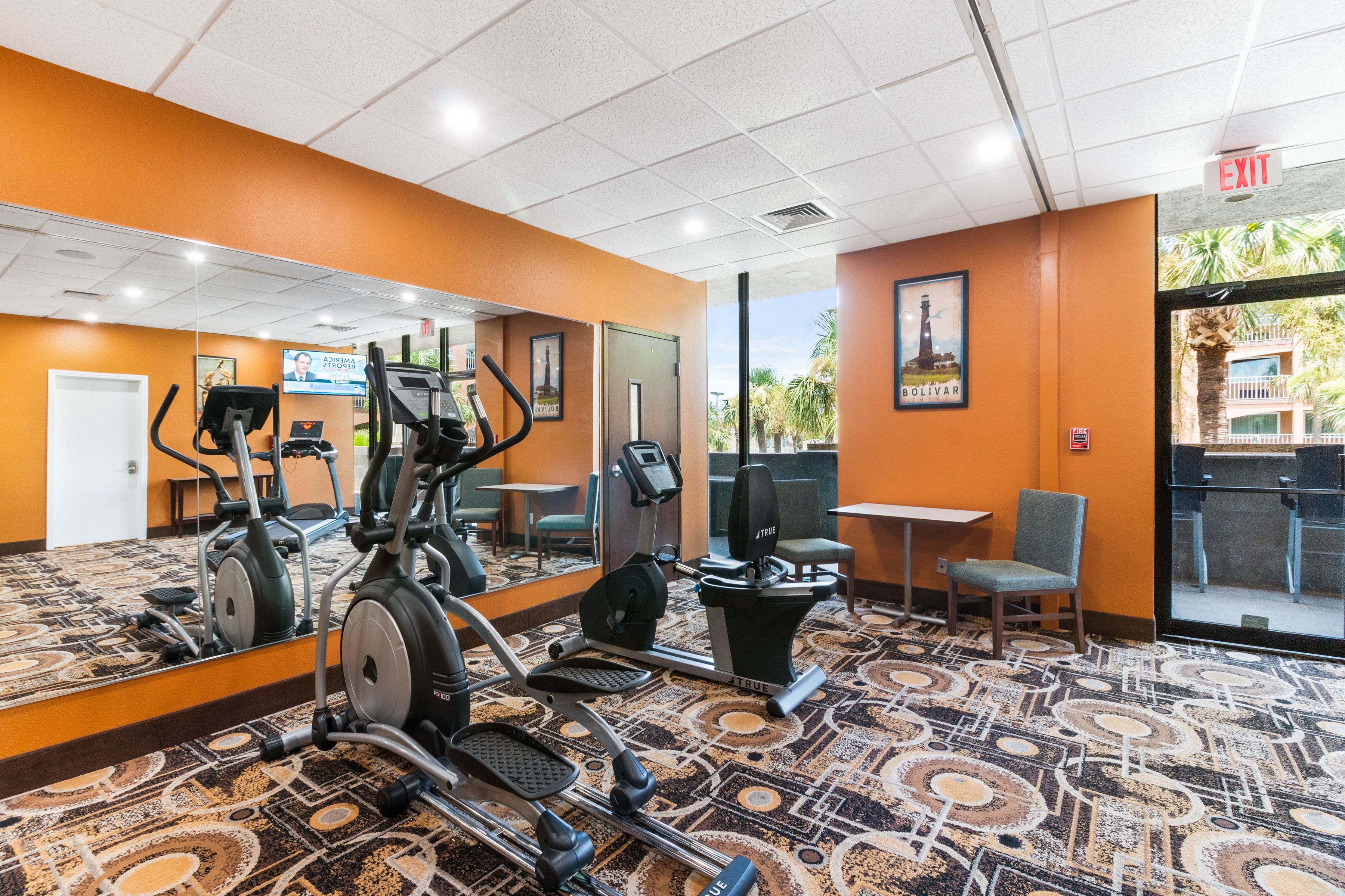 Un gimnasio con equipo de ejercicio, un espejo y vistas al exterior.
