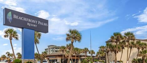 Naamplaatje voor Beachfront Palms Resort, met een heldere lucht en palmbomen.