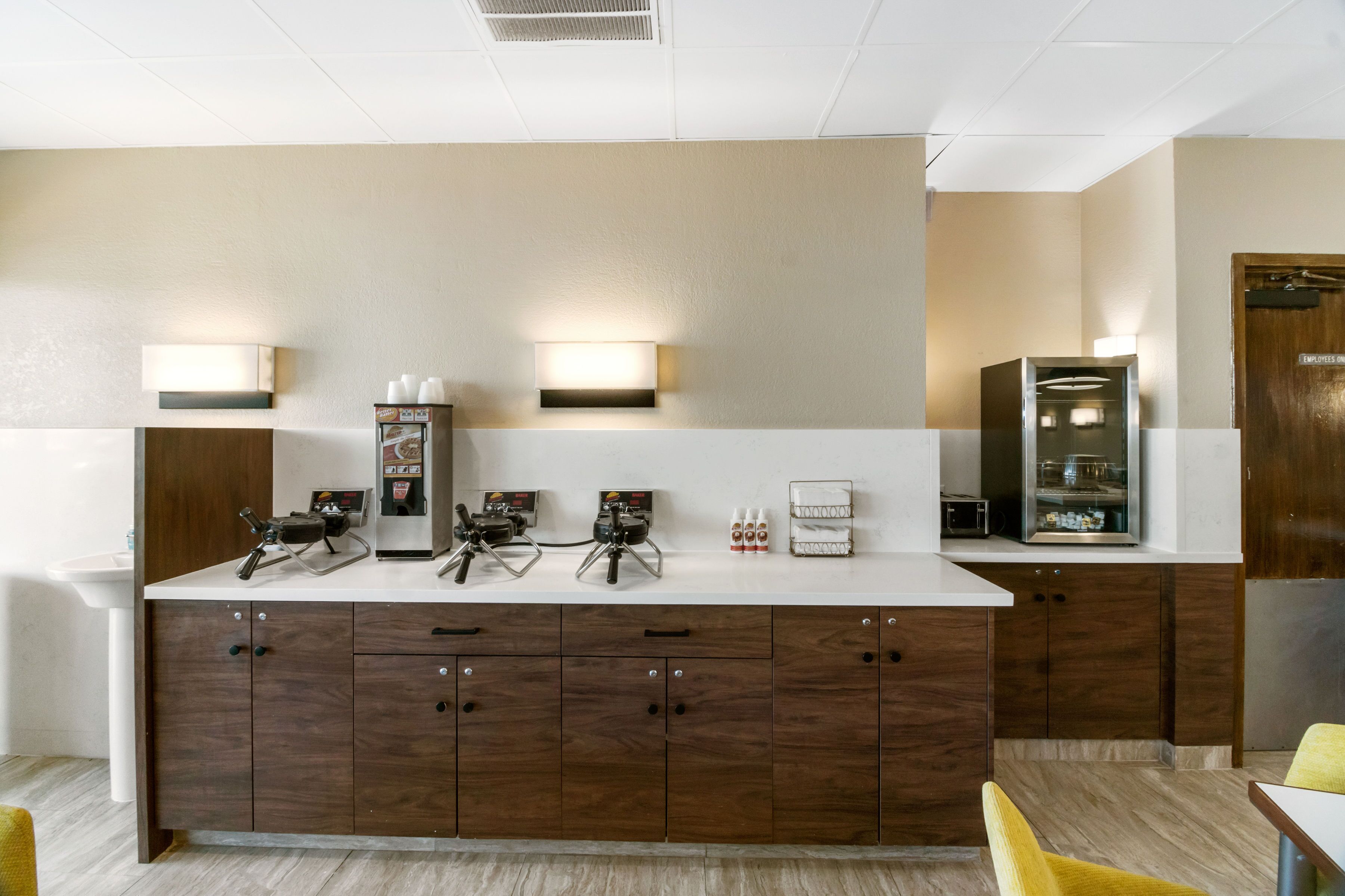Una cocina moderna con encimera blanca, armarios de madera y dos apliques.