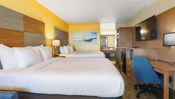 Habitación de hotel con una cama grande, un escritorio con silla, una lámpara de escritorio, un televisor de pantalla plana, un refrigerador y un cuadro en la pared.