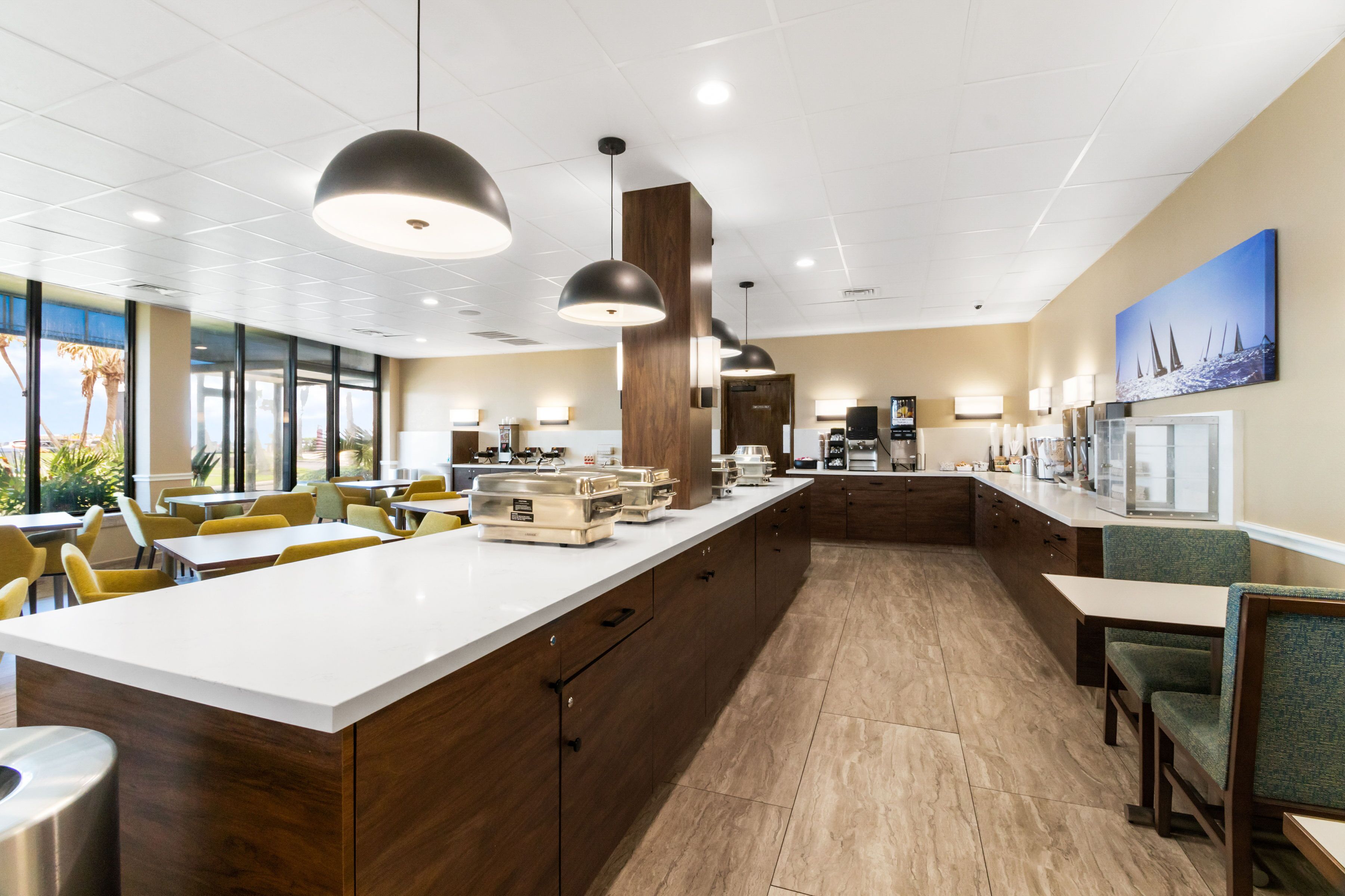 A modern hotel lobby with a central island, seating areas, and a coffee station.