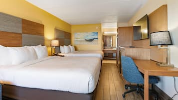 Une chambre d’hôtel avec deux lits, un bureau, une chaise, une lampe, un tableau et un miroir.