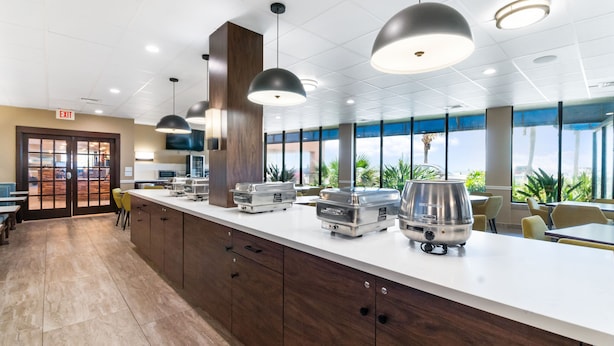 Una cocina moderna con una encimera larga, electrodomésticos de acero inoxidable e iluminación colgante.