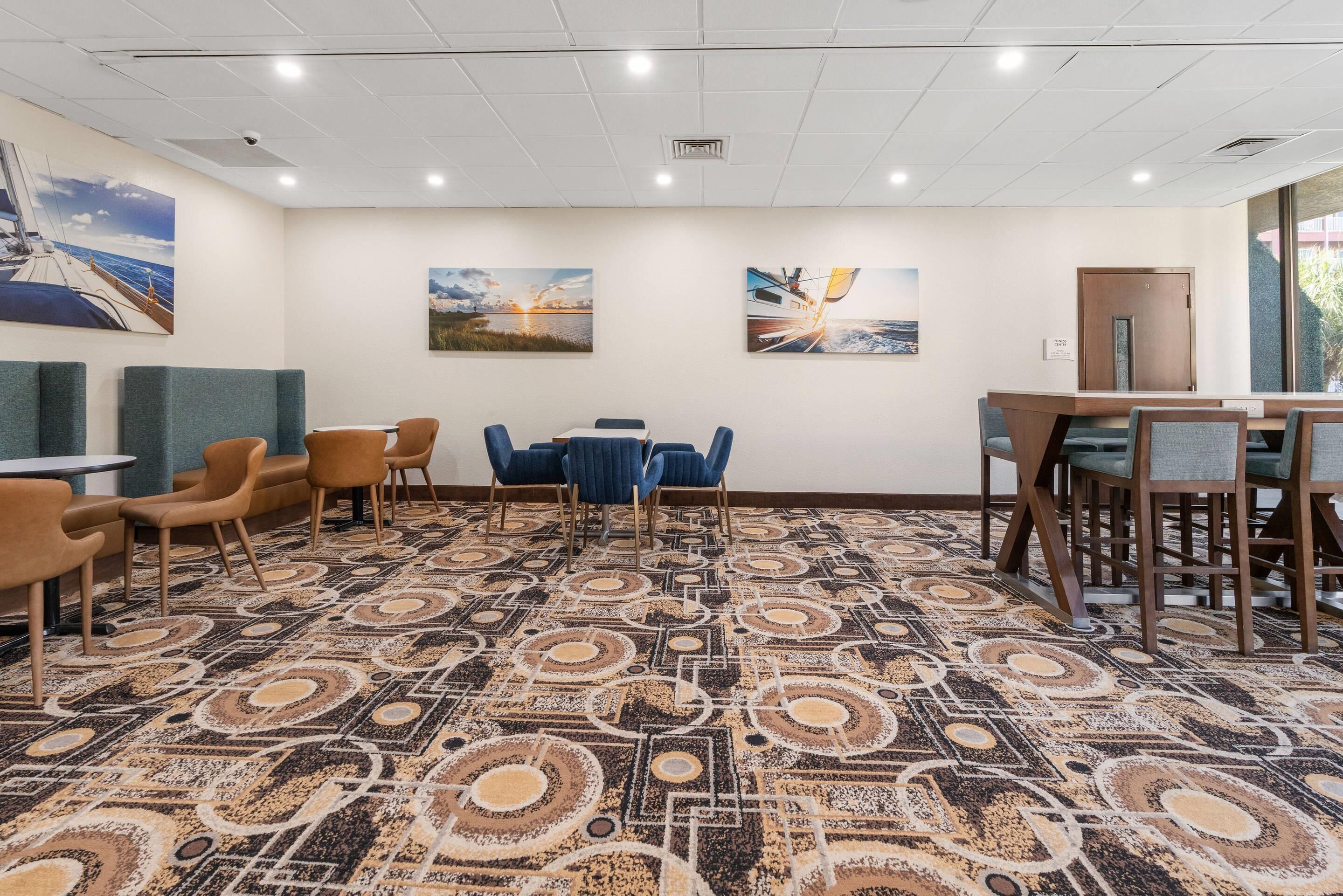 A conference room with a patterned carpet, blue and brown chairs, and two paintings on the wall.