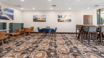 A conference room with a patterned carpet, blue and brown chairs, and two paintings on the wall.