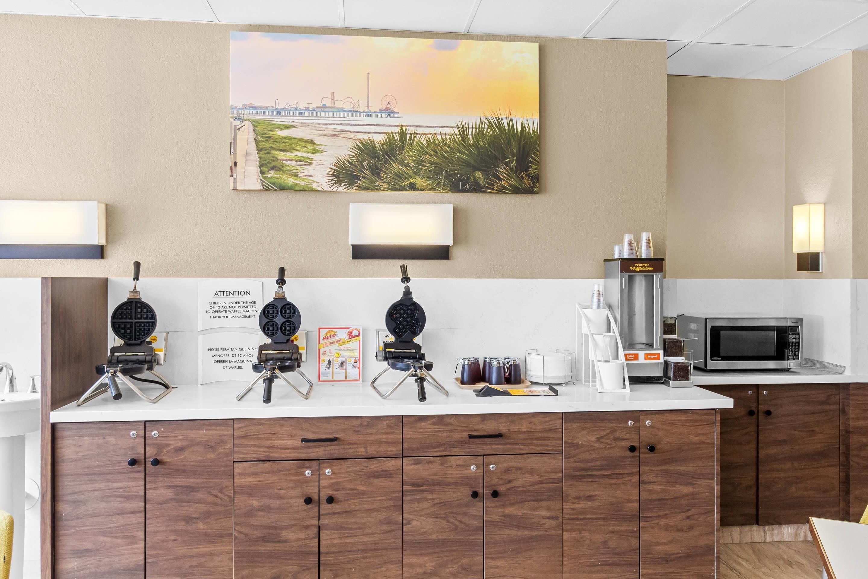 Une cuisine d’hôtel équipée d’un appareil à gaufres, d’une machine à café et d’un four à micro-ondes.