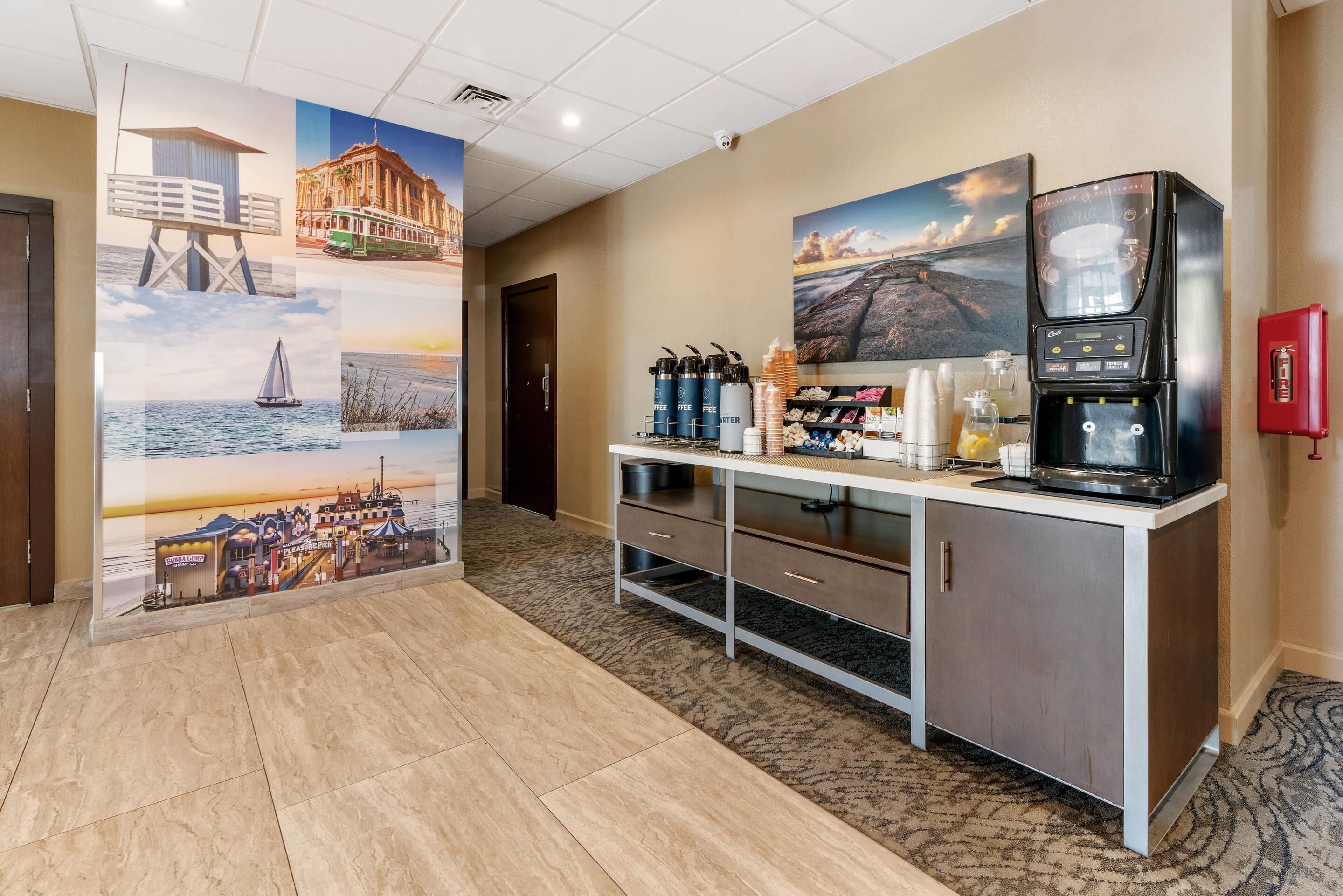 Eine Hotelhalle mit einer Rezeption, einer Kaffeemaschine und einer Wand mit verschiedenen Landschaftsbildern.