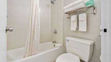 Une salle de bain équipée d’une baignoire, de toilettes et d’un porte-serviettes avec des serviettes pliées.
