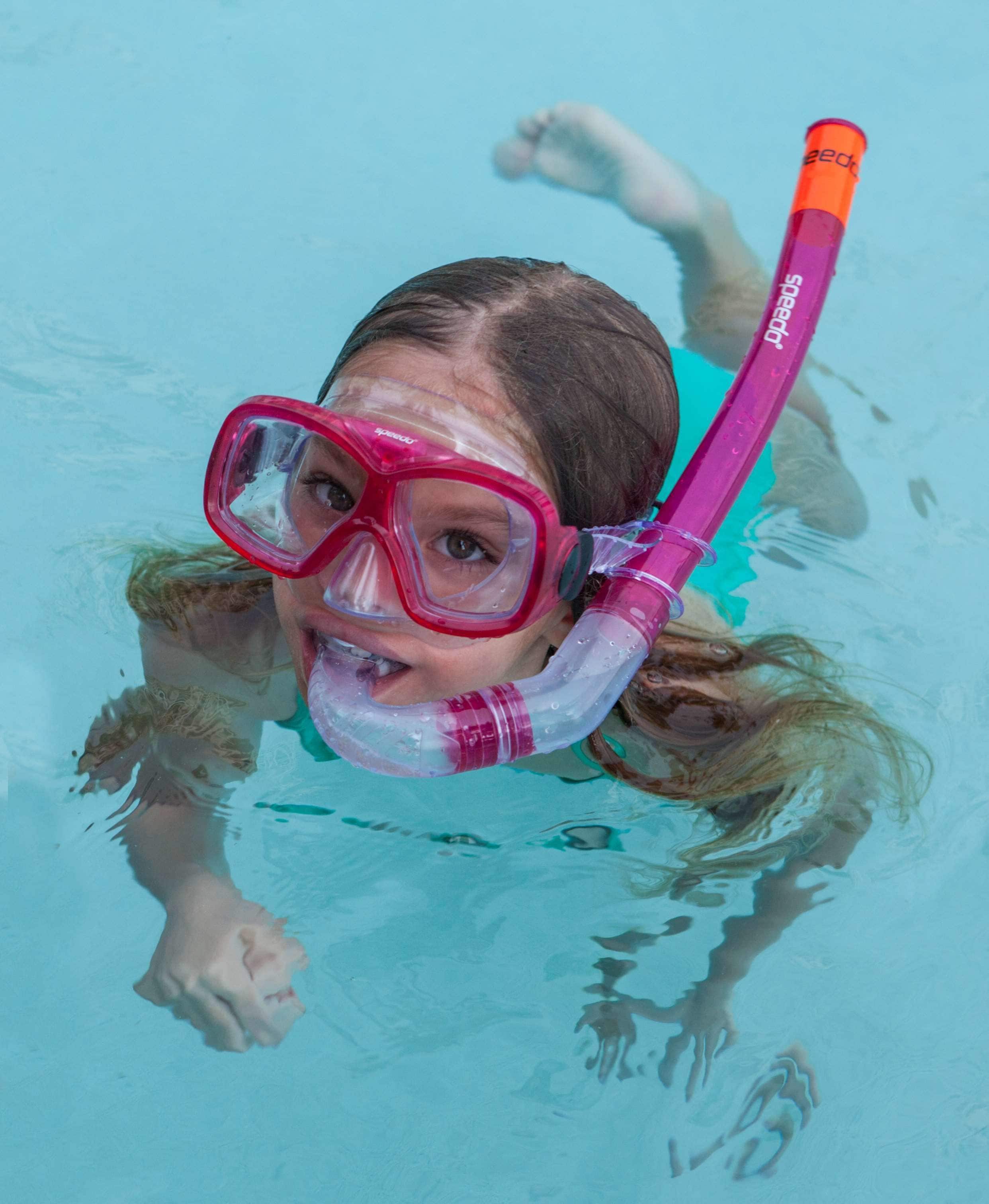 A person swimming in a pool with a snorkel and mask.