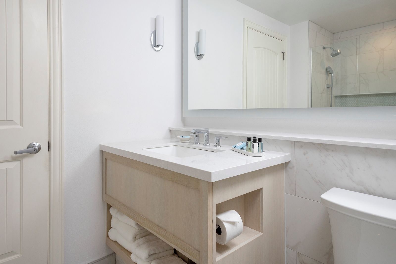 A bathroom with a white sink, mirror, and toilet.