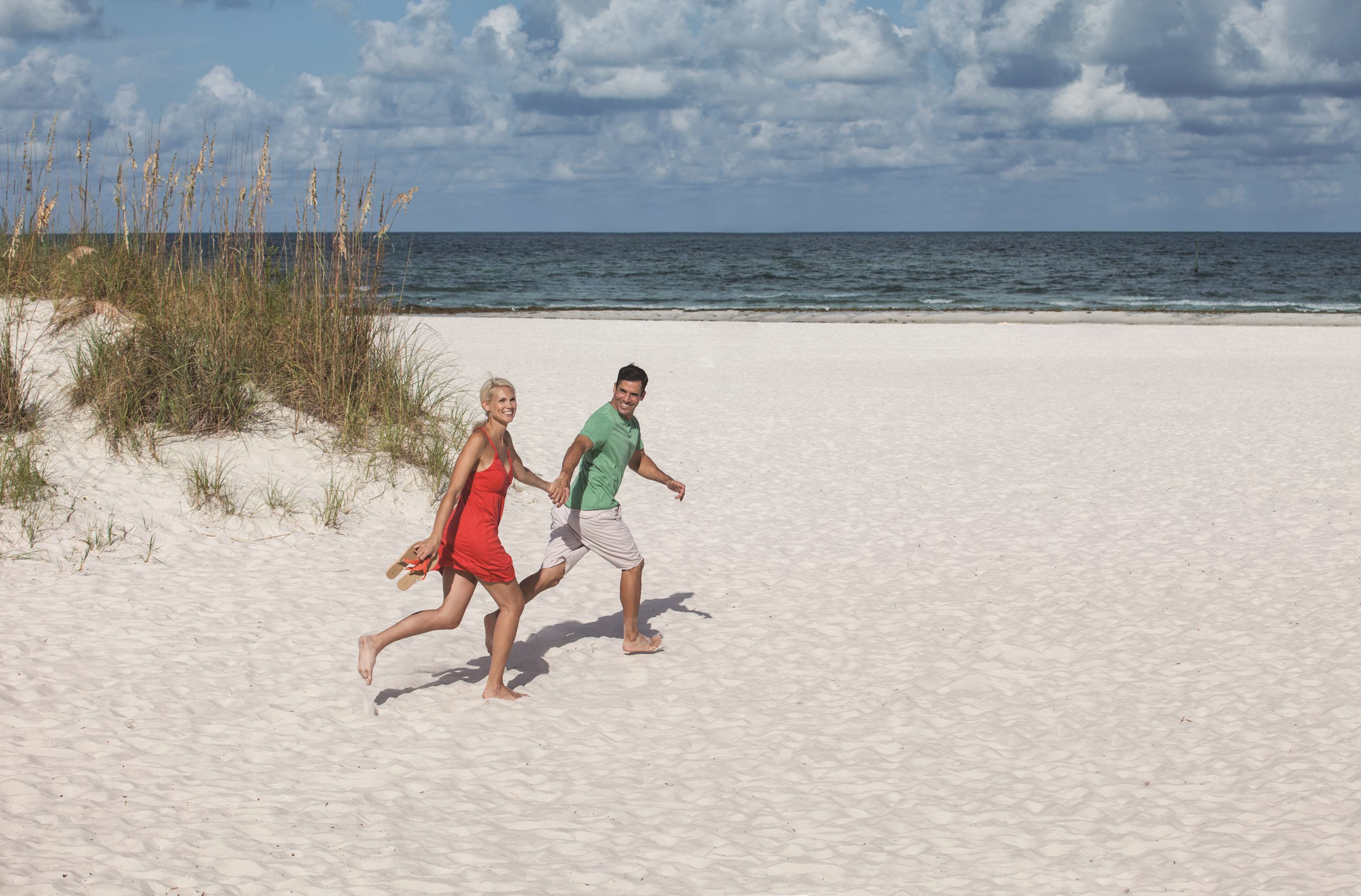 A sandy beach with two people running.