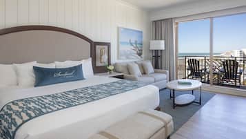 Habitación de hotel con una cama grande, un sofá, una mesita y un balcón con vista a la playa.