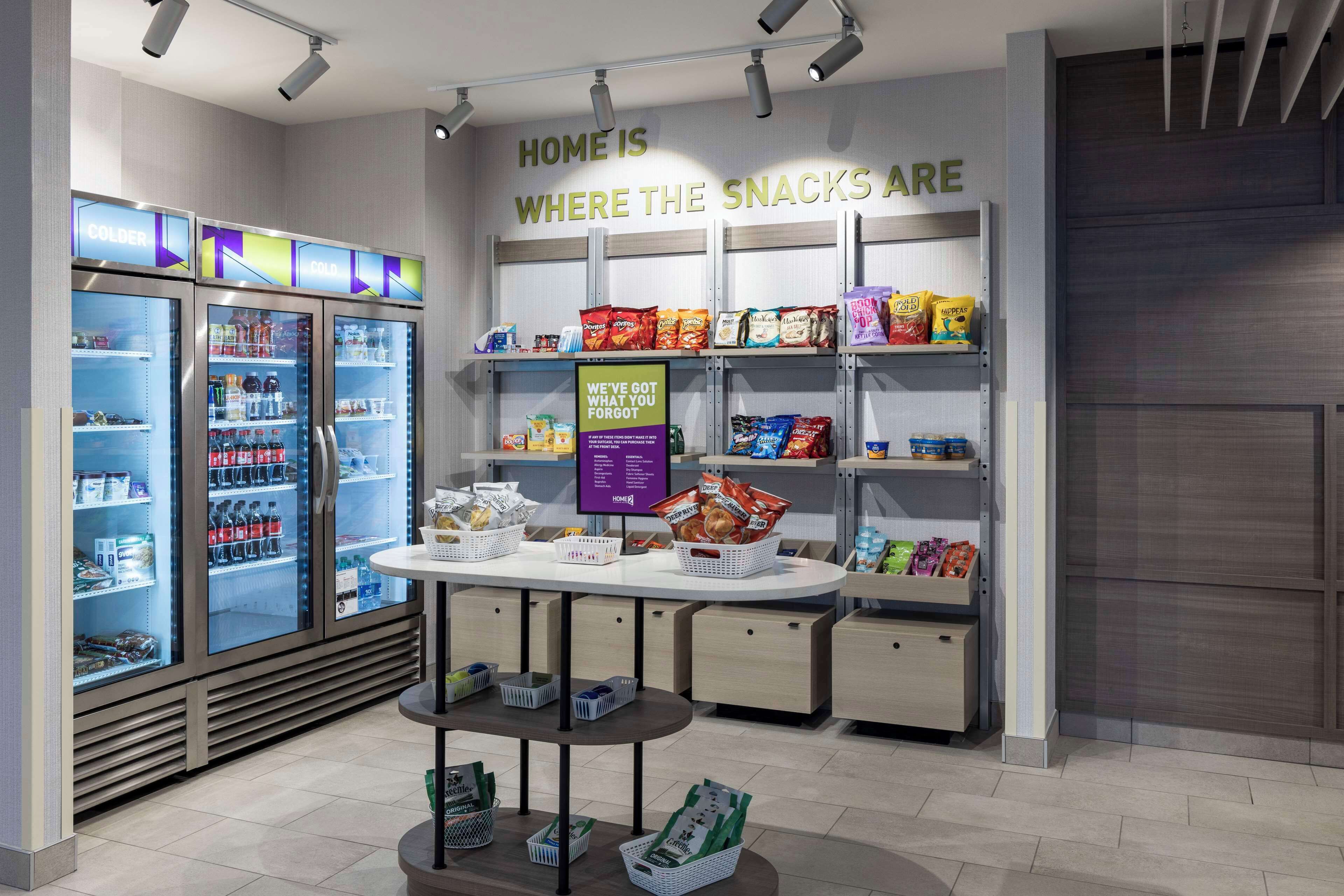 A snack section in a store with refrigerated and shelf displays, a sign about forgotten snacks, and a checkout counter.
