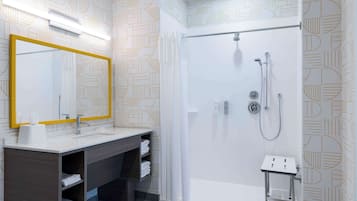 Un baño moderno con un espejo grande, ducha y tocador con estantes.