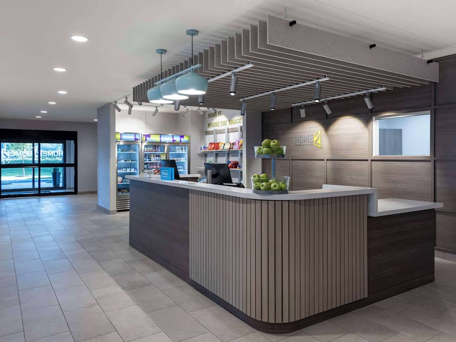 A modern reception area with a counter, shelves with snacks, and a view of the outside.