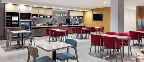 A modern restaurant with multiple dining tables and chairs, a kitchen area, and a 'RISE & DINE' sign.