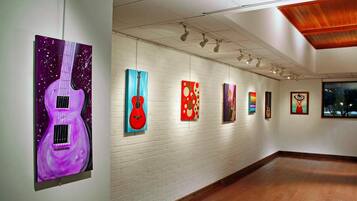 Una galería de arte con pared de ladrillo blanco y suelo de madera.