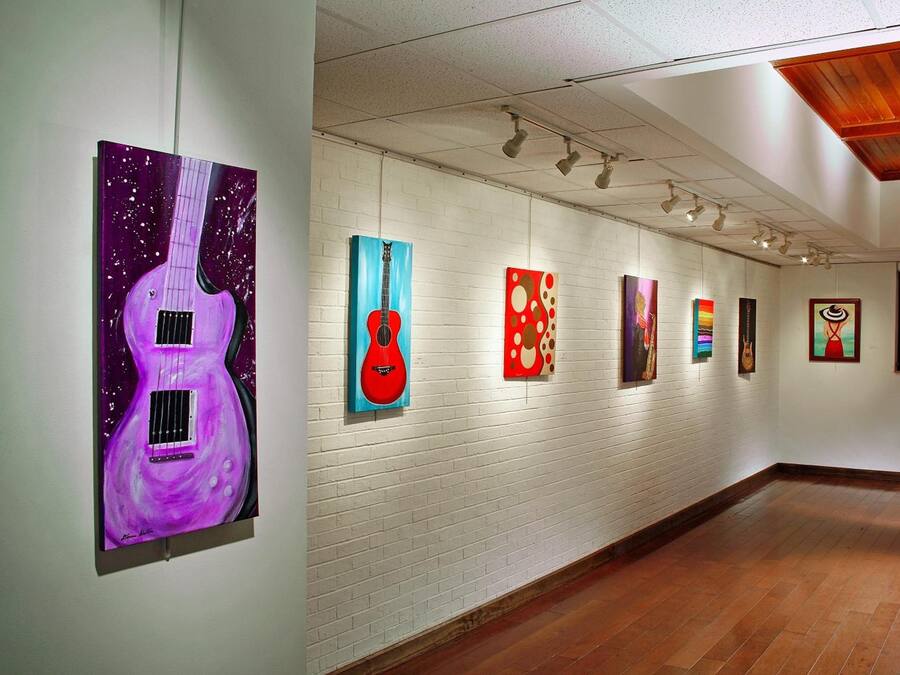 Una galería de arte con pared de ladrillo blanco y suelo de madera.