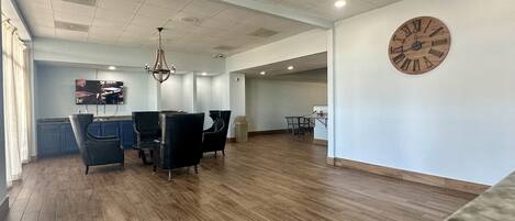 A spacious room with wooden flooring, a chandelier, and a large wooden clock on the wall.