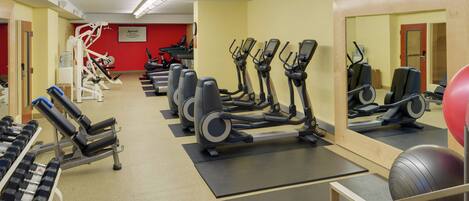 A gym with treadmills, elliptical machines, and free weights.