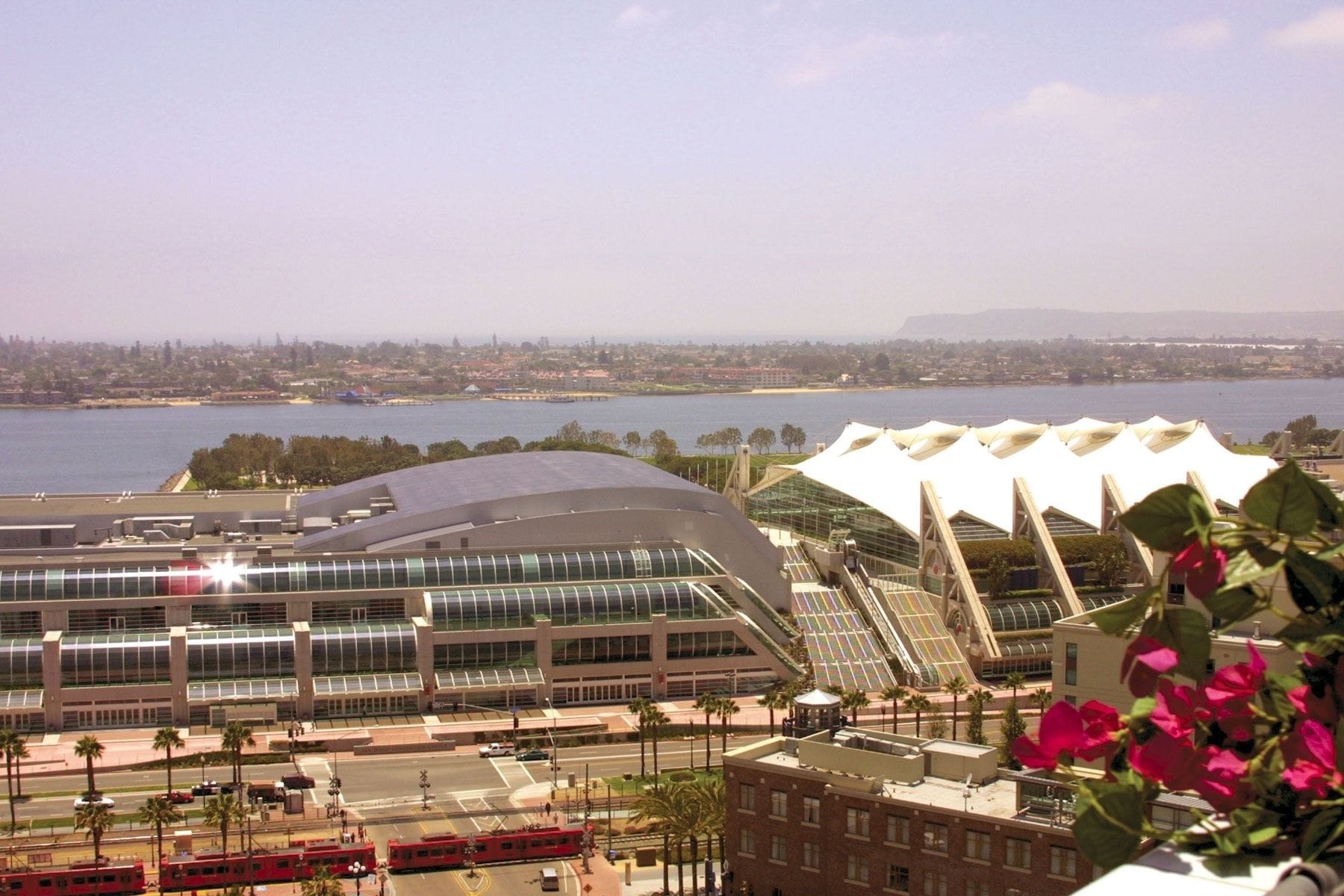 A modern building with a curved glass facade and a large, white, tent-like structure in the background.