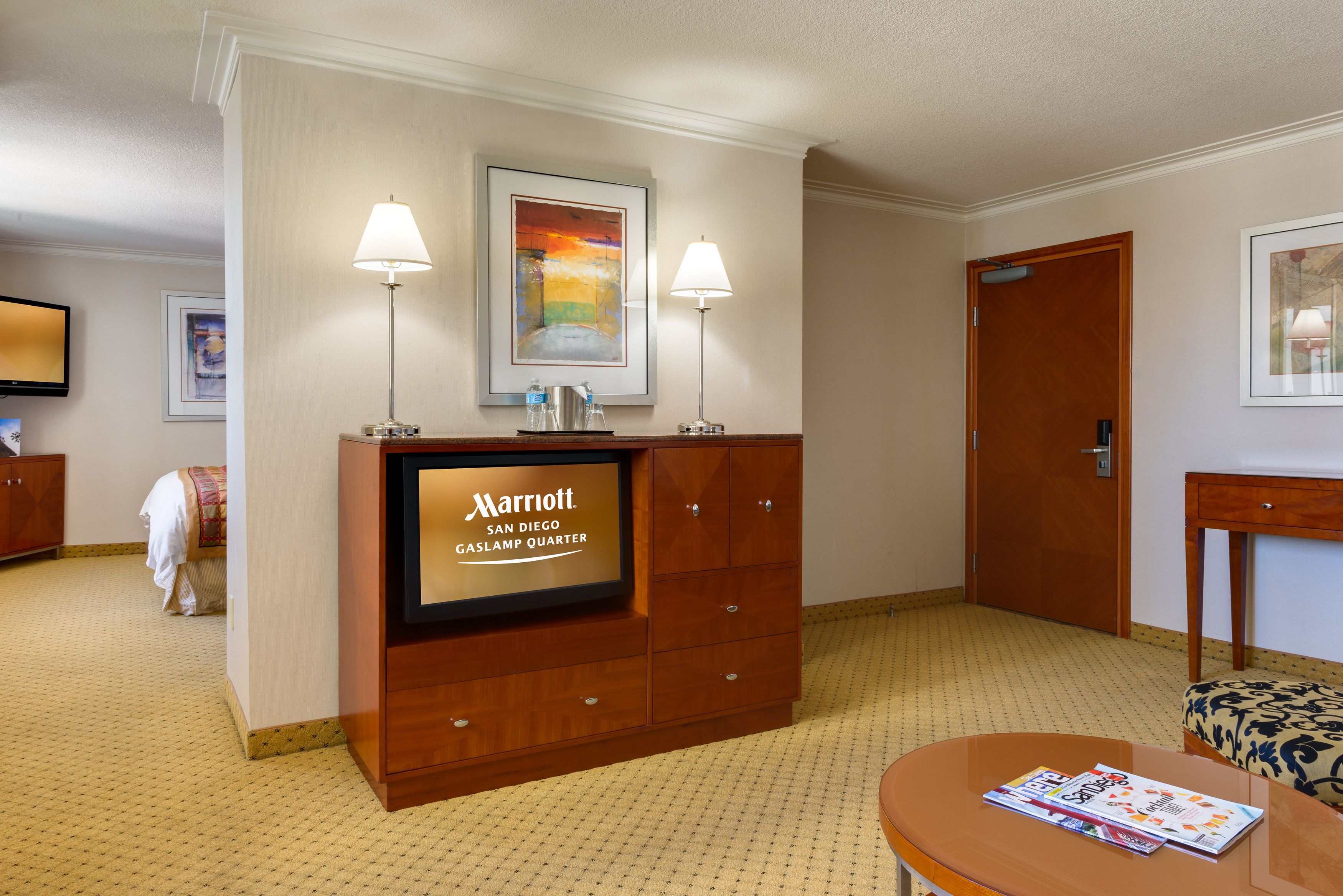 En hotellobby med en receptionsdisk, inramade konstverk, en tv och en sittgrupp.