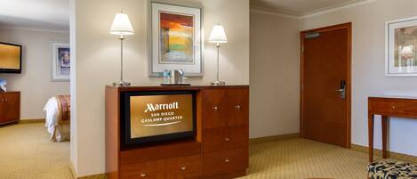 En hotellobby med en receptionsdisk, inramade konstverk, en tv och en sittgrupp.