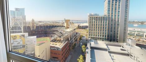 A view of a stadium with a baseball field, a bridge, and modern buildings in the background.