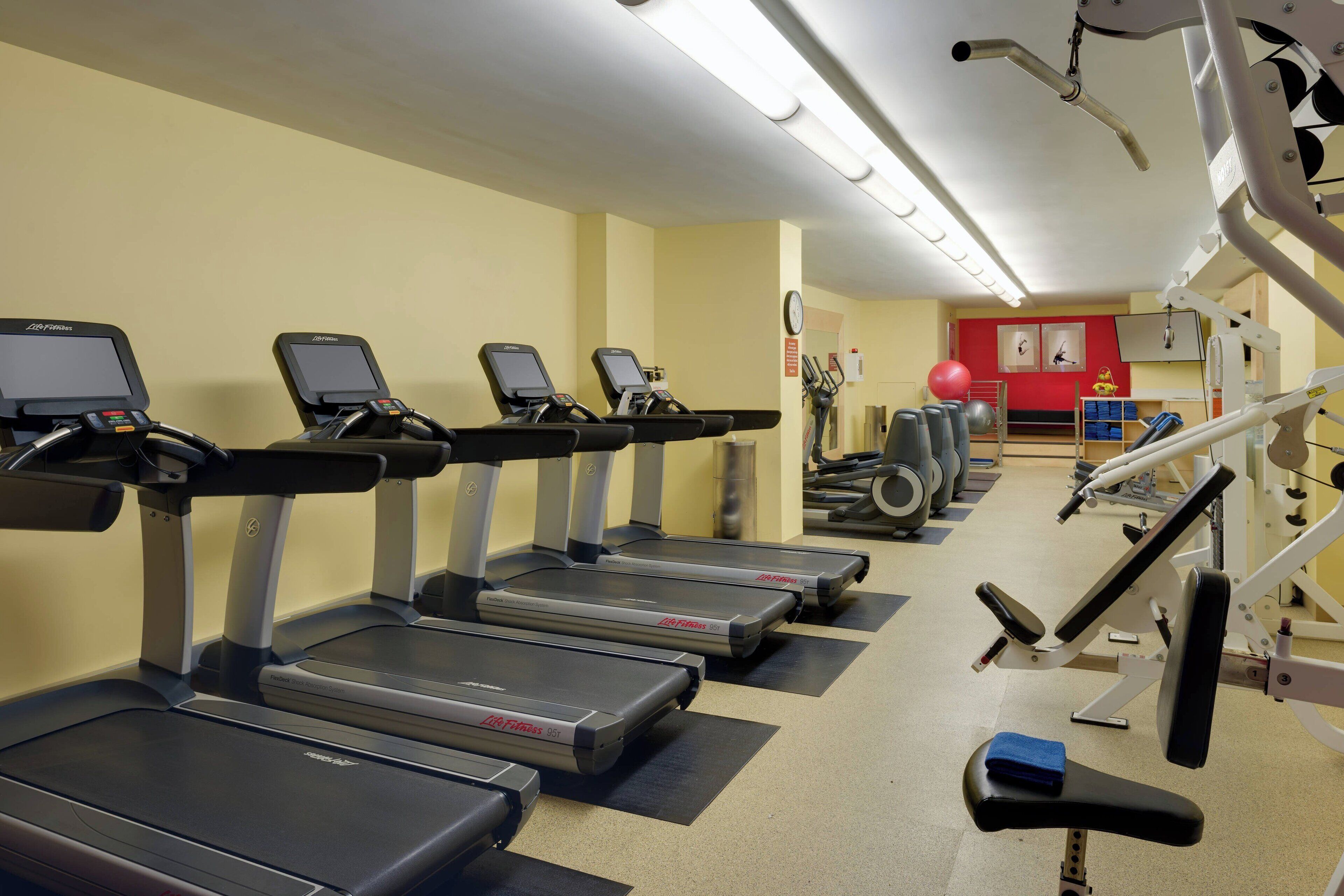 Ein Fitnessraum mit Laufbändern, Krafttrainingsgeräten und Übungsbällen.
