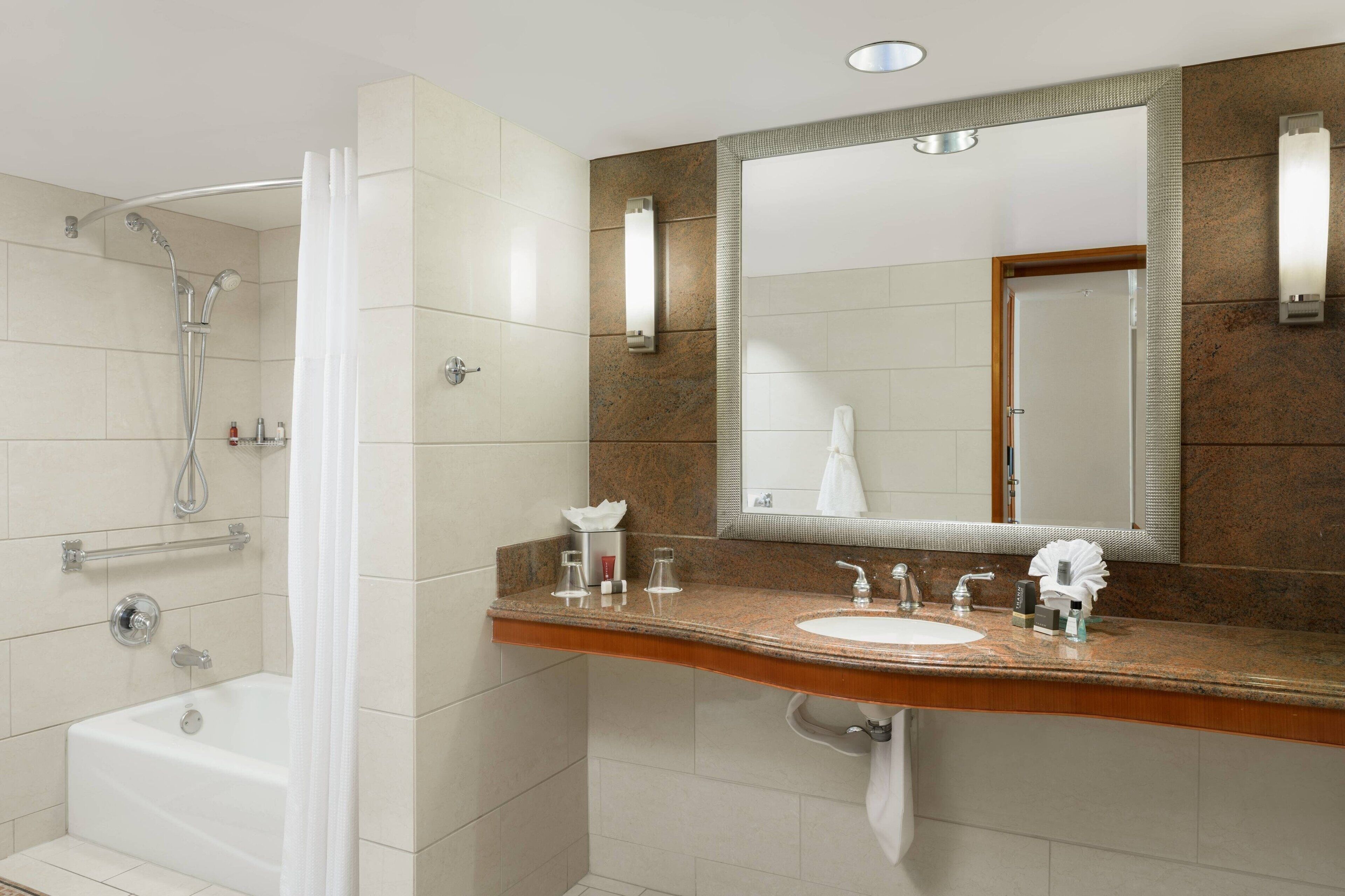 Un baño moderno con bañera, ducha y tocador con lavabo y espejo.