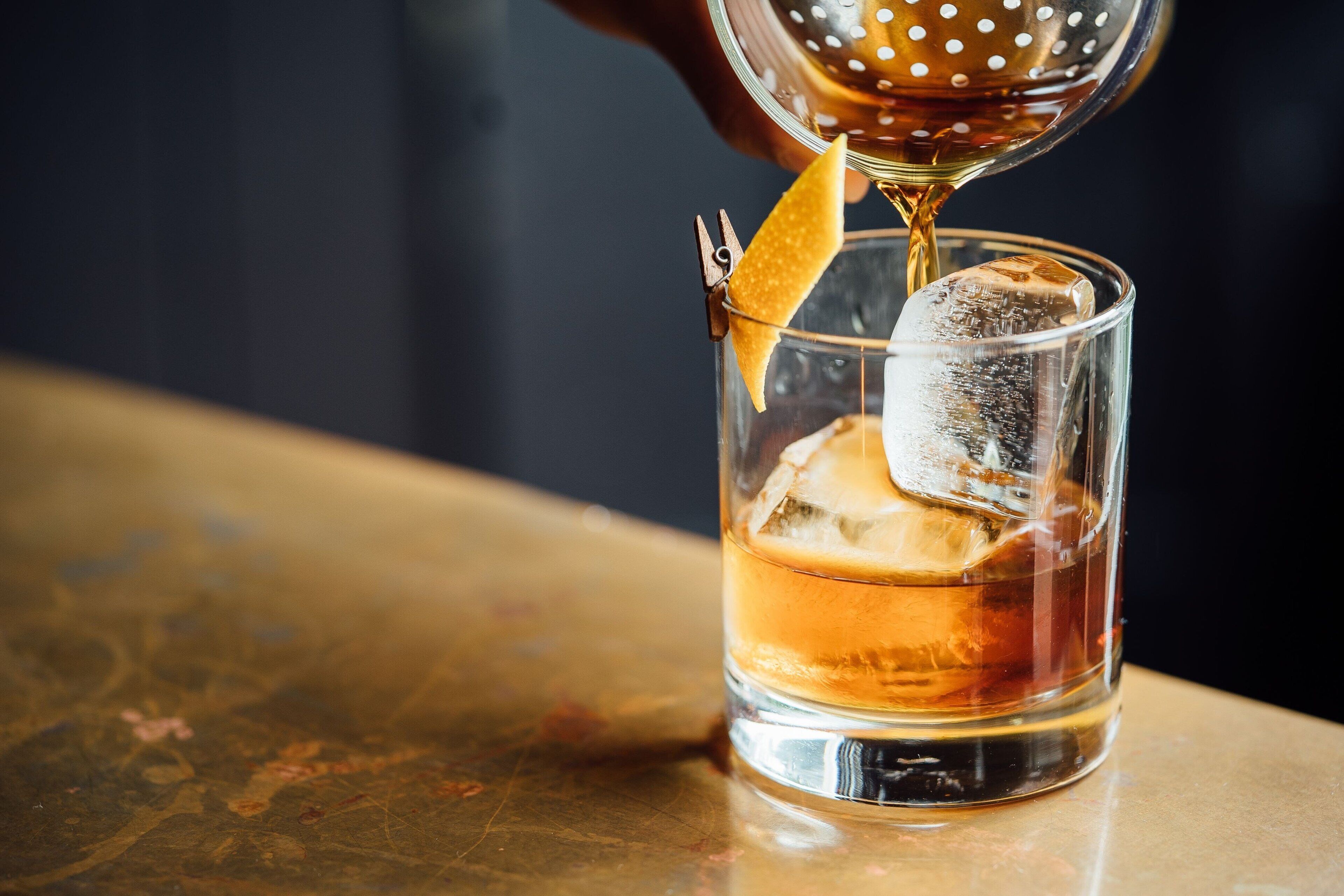 Un verre transparent contenant des glaçons et dans lequel on verse un liquide.