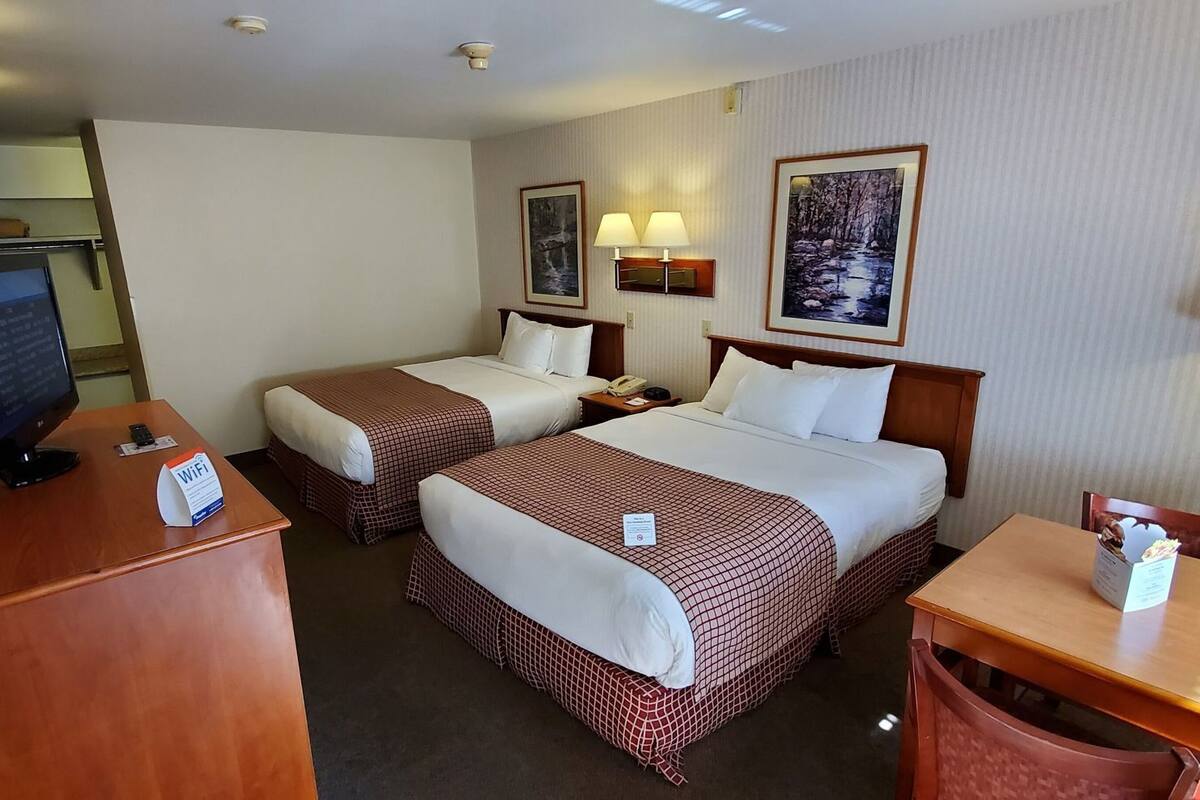 Een hotelkamer met twee bedden, een bureau, een televisie en een bureaulamp.