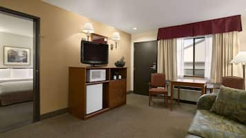 A hotel room with a bed, a television, a desk with a chair, a sofa, and a microwave.