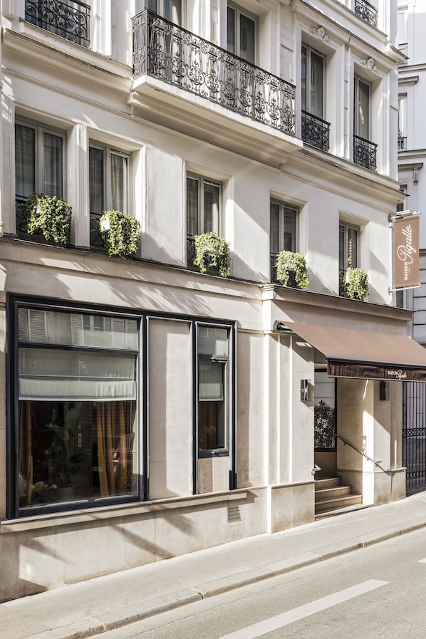 A building with a white facade, large windows, and a brown awning.