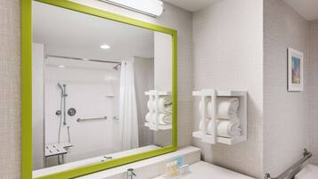A bathroom with a large mirror, a sink, a toilet, and a shower area.