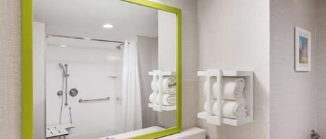 Une salle de bain avec un grand miroir, un lavabo, des toilettes et un espace douche.