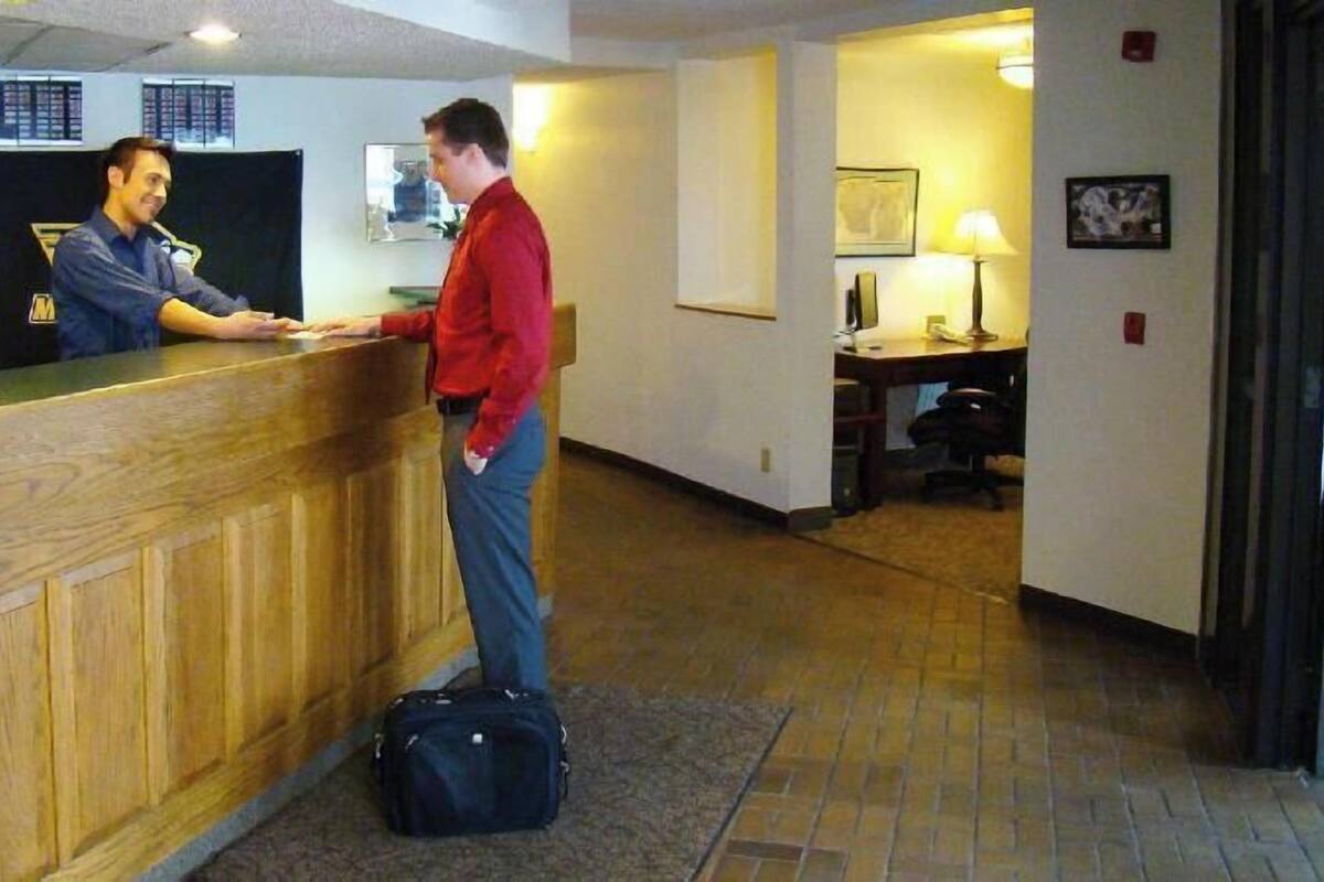 Een receptiebalie van hout, een bureau met een lamp en een stoel.