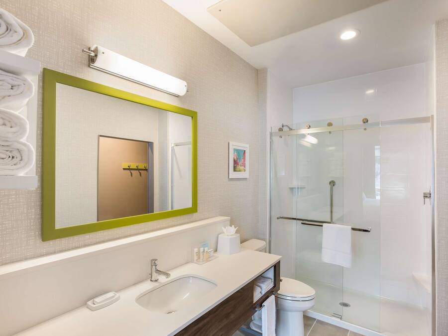 A modern bathroom with a large mirror, a sink, a toilet, and a glass-enclosed shower.