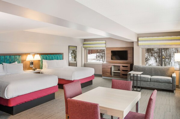 Una habitación de hotel con dos camas, un sofá, un televisor y un comedor.