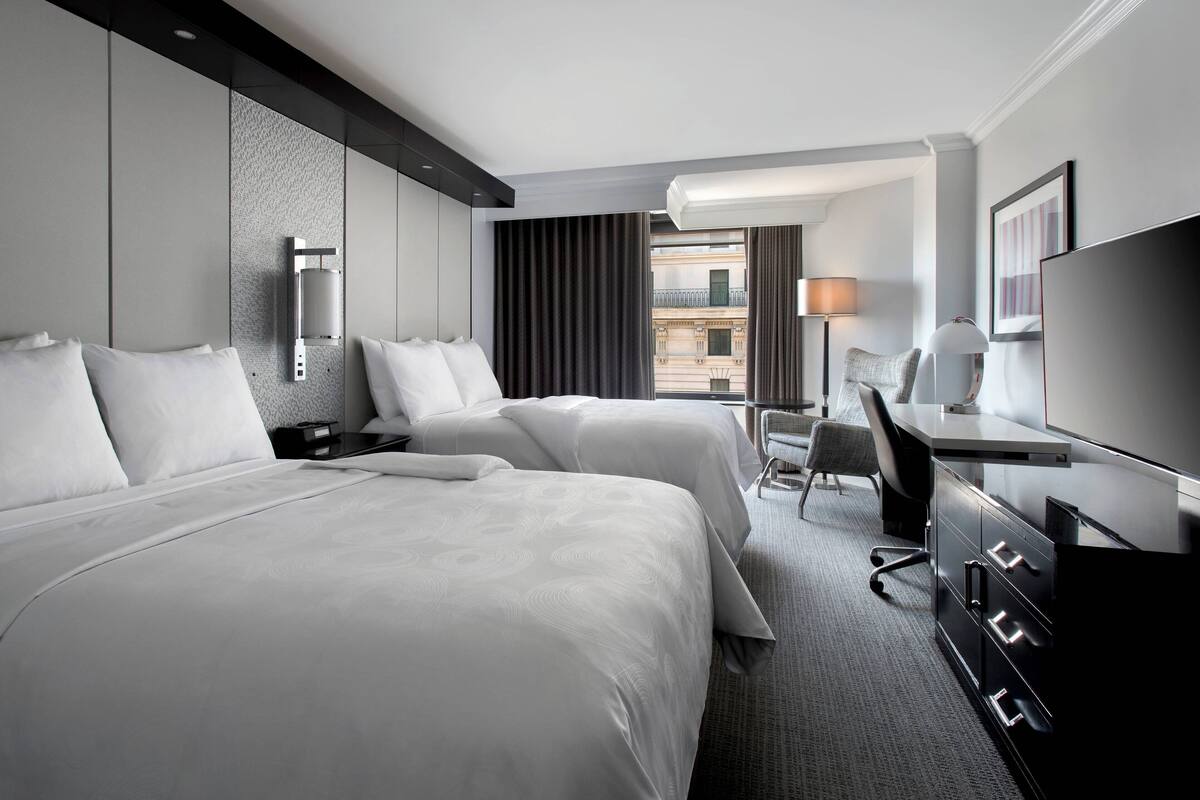 Een hotelkamer met twee bedden, een bureau, een stoel en een televisie.