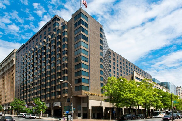 A large hotel with a prominent American flag on top, multiple floors, and a clear view of the street in front.