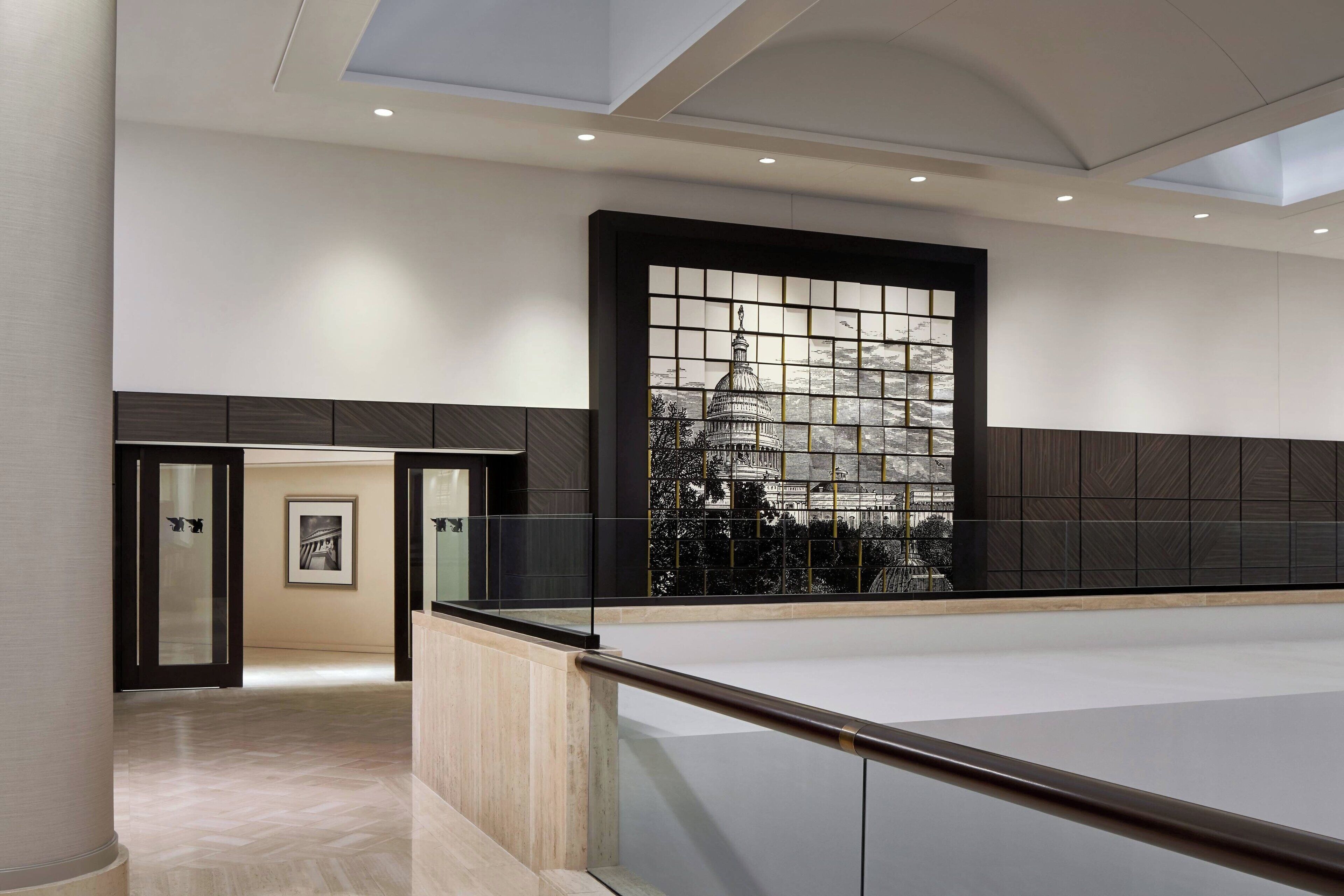 Eine großzügige Lobby mit hoher Decke, einer großen Glaswand mit Blick auf die Stadtlandschaft und einem modernen Design mit Holzpaneelen und Marmorboden.