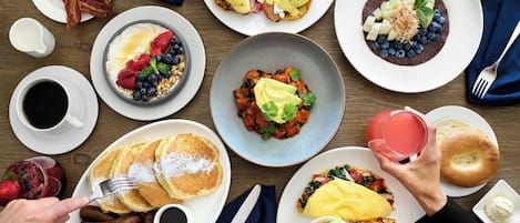 A breakfast setting with various dishes including pancakes, eggs, bacon, and a variety of fruits and vegetables.