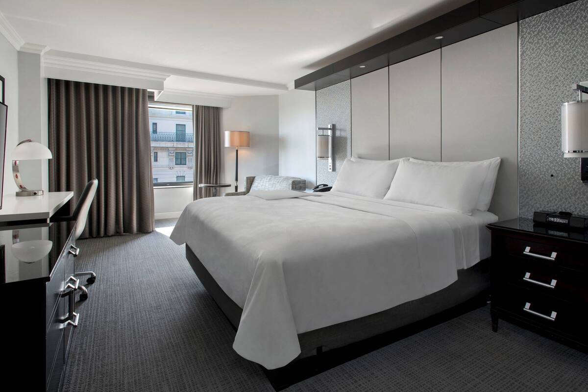 Een moderne hotelkamer met een groot bed, een bureau, een stoel en een nachtkastje.
