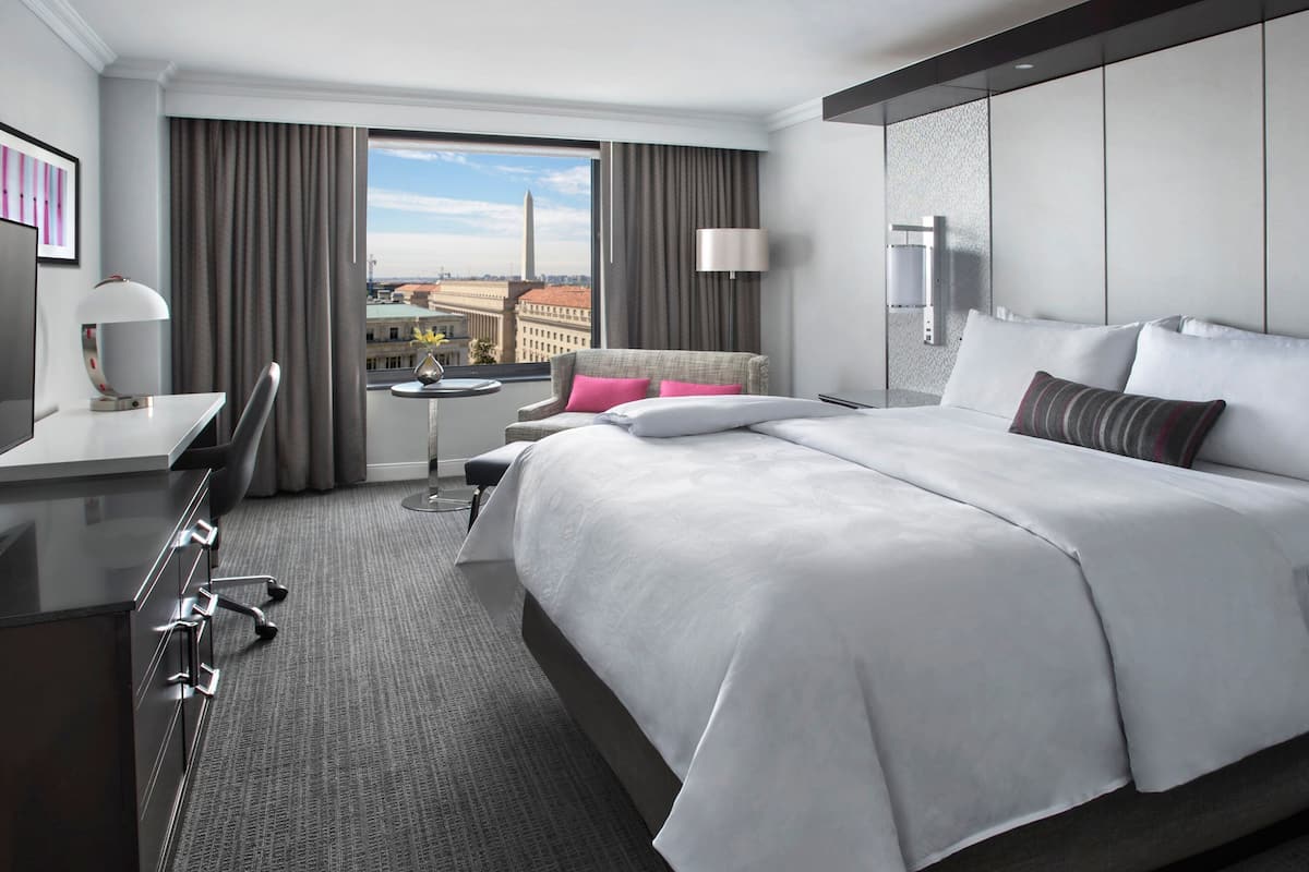 Een moderne hotelkamer met een groot bed, een bureau en uitzicht op een stadsbeeld.