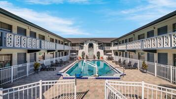 Relax by the central pool surrounded by lush greenery and lounge chairs.